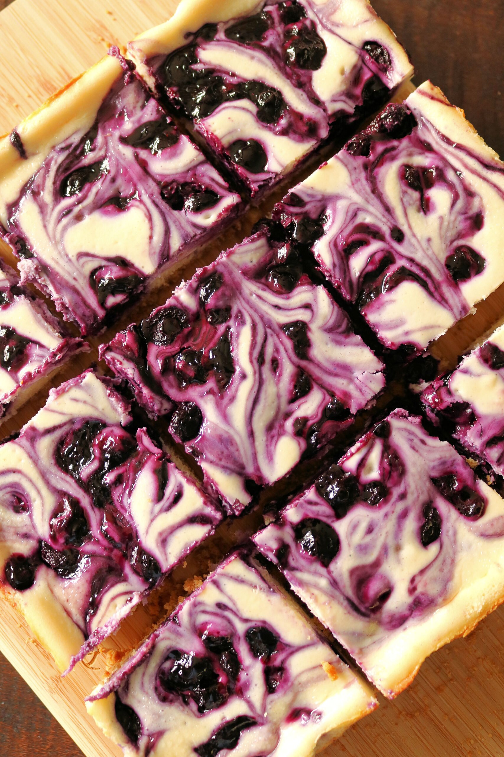 These easy and delicious Blueberry Swirl Cheesecake Bars are the best blueberry cheesecake bars you'll ever eat! Creamy vanilla and lemon cheesecake filling is swirled with a homemade blueberry sauce and baked on a buttery graham cracker crust. Give these easy blueberry cream cheese bars a try for dessert!