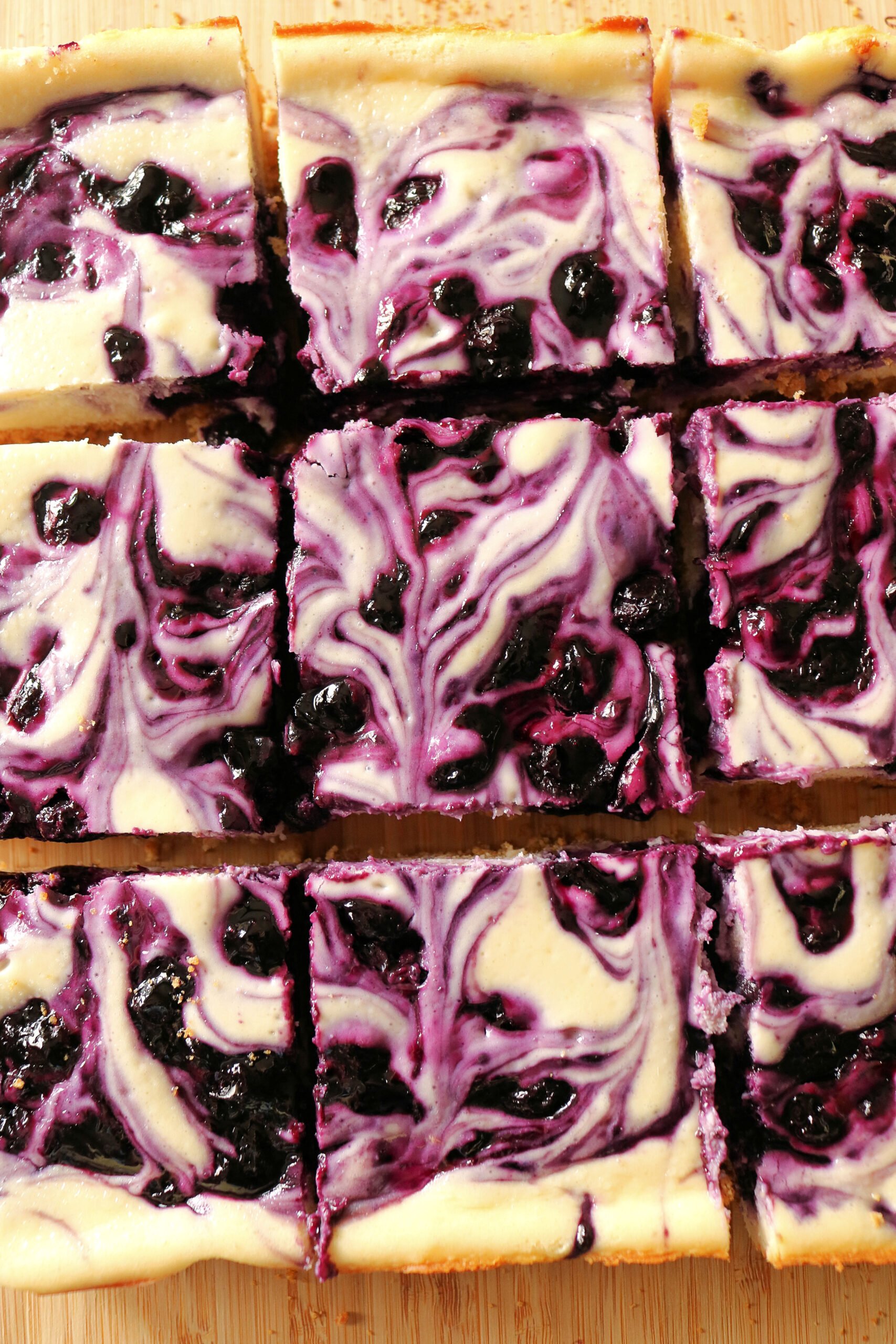 These easy and delicious Blueberry Swirl Cheesecake Bars are the best blueberry cheesecake bars you'll ever eat! Creamy vanilla and lemon cheesecake filling is swirled with a homemade blueberry sauce and baked on a buttery graham cracker crust. Give these easy blueberry cream cheese bars a try for dessert!