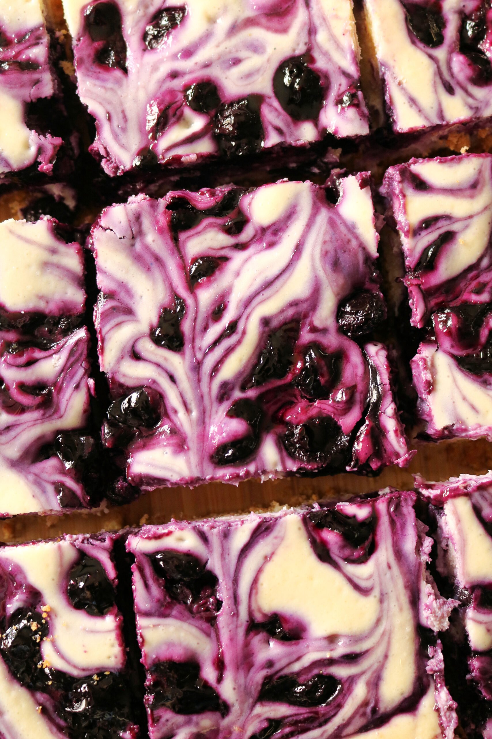 These easy and delicious Blueberry Swirl Cheesecake Bars are the best blueberry cheesecake bars you'll ever eat! Creamy vanilla and lemon cheesecake filling is swirled with a homemade blueberry sauce and baked on a buttery graham cracker crust. Give these easy blueberry cream cheese bars a try for dessert!